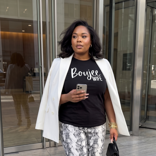 Woman wearing a black t-shirt with 'Boujee Wife' text, standing outside a building.