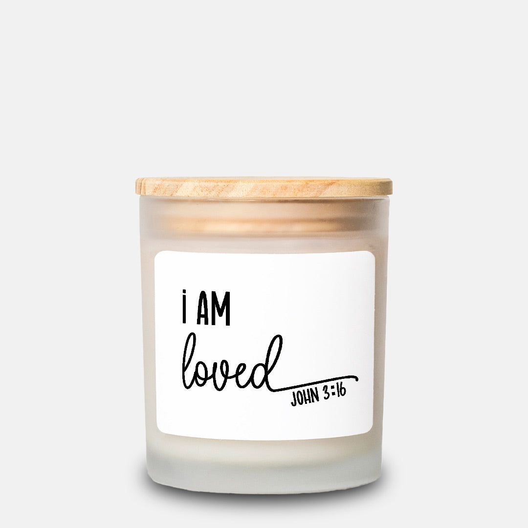 Candle with a wooden lid and 'I AM loved' label on a white background